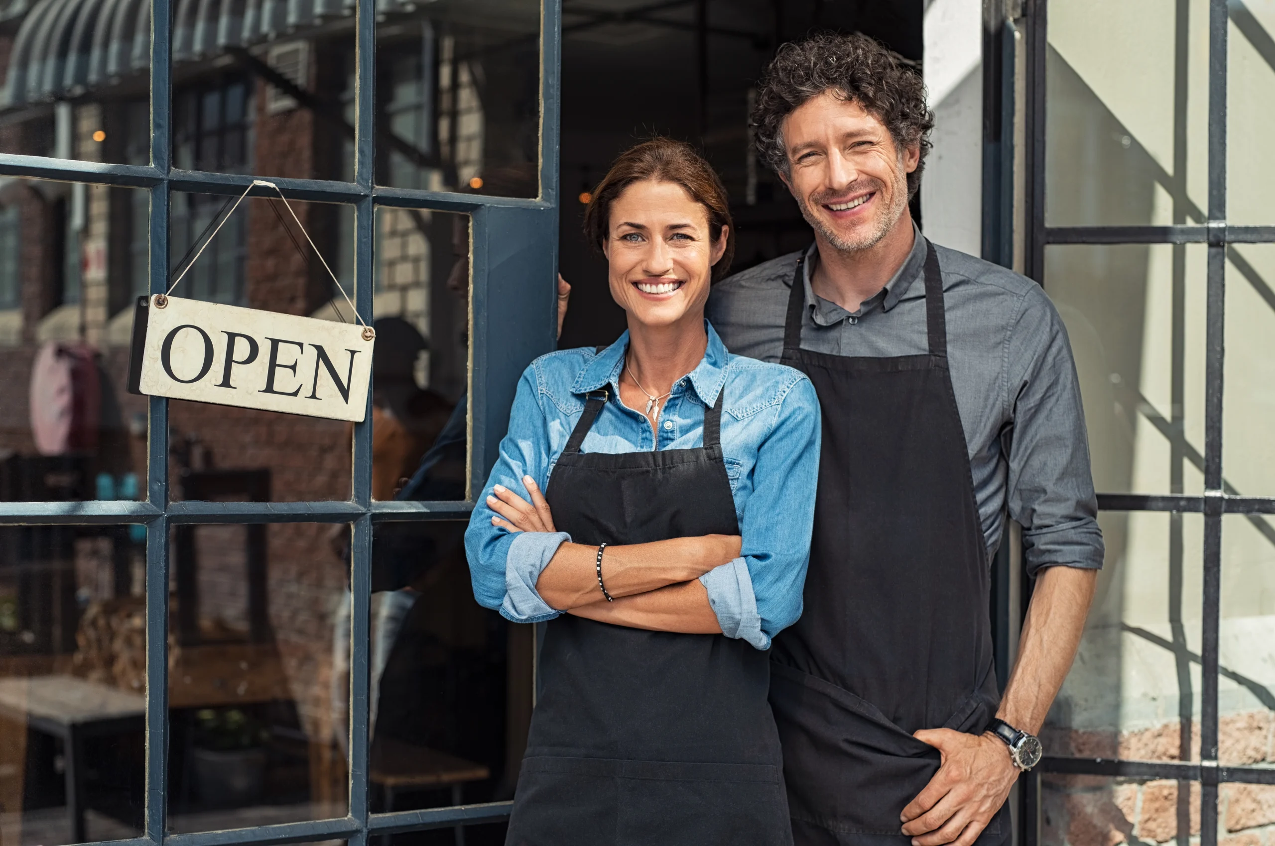 Small business owners smiling in front of their store